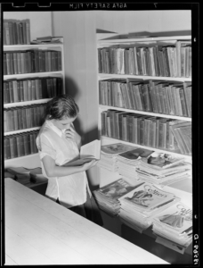 Girl in a migrant camp library during the depression, 